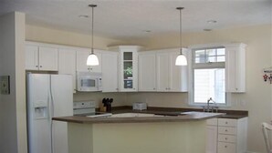 A kitchen with white cabinets, a microwave, a refrigerator, a sink, and a window. - 343 Oak Ave in Lakeside (Lakeside)