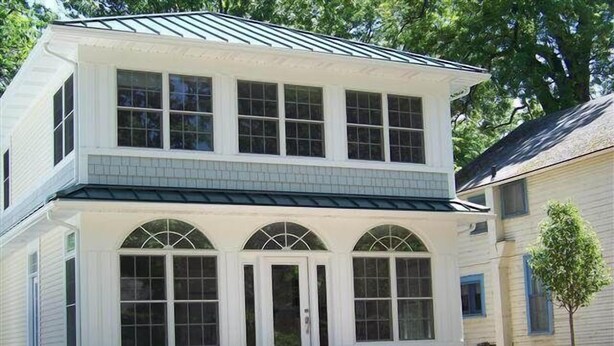 A two-story house with a covered front porch, large windows, and a small patio area with chairs. - 343 Oak Ave in Lakeside (Lakeside)