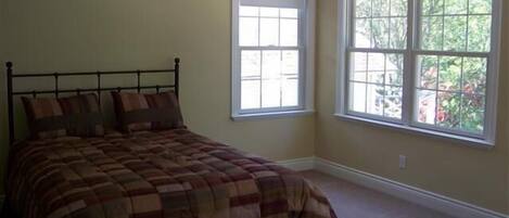 Une chambre à coucher avec un lit, deux fenêtres et un ventilateur de plafond.