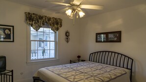 A bedroom with a bed, a ceiling fan, a window with a view, and a small table with a vase. - 533 Sycamore in Lakeside (Lakeside)