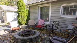 A patio with outdoor furniture, a fire pit, and a house in the background.