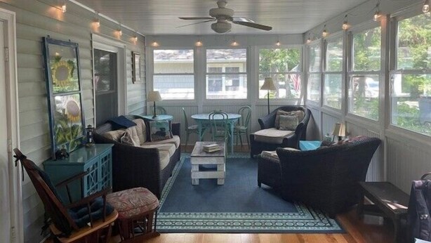 A sunroom with a ceiling fan, a sofa, a coffee table, and a dining table with chairs.