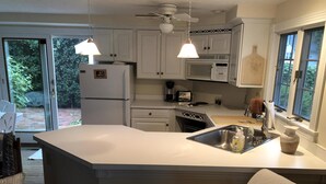 A kitchen with a central island, white cabinets, a microwave, a stove, and a sink.