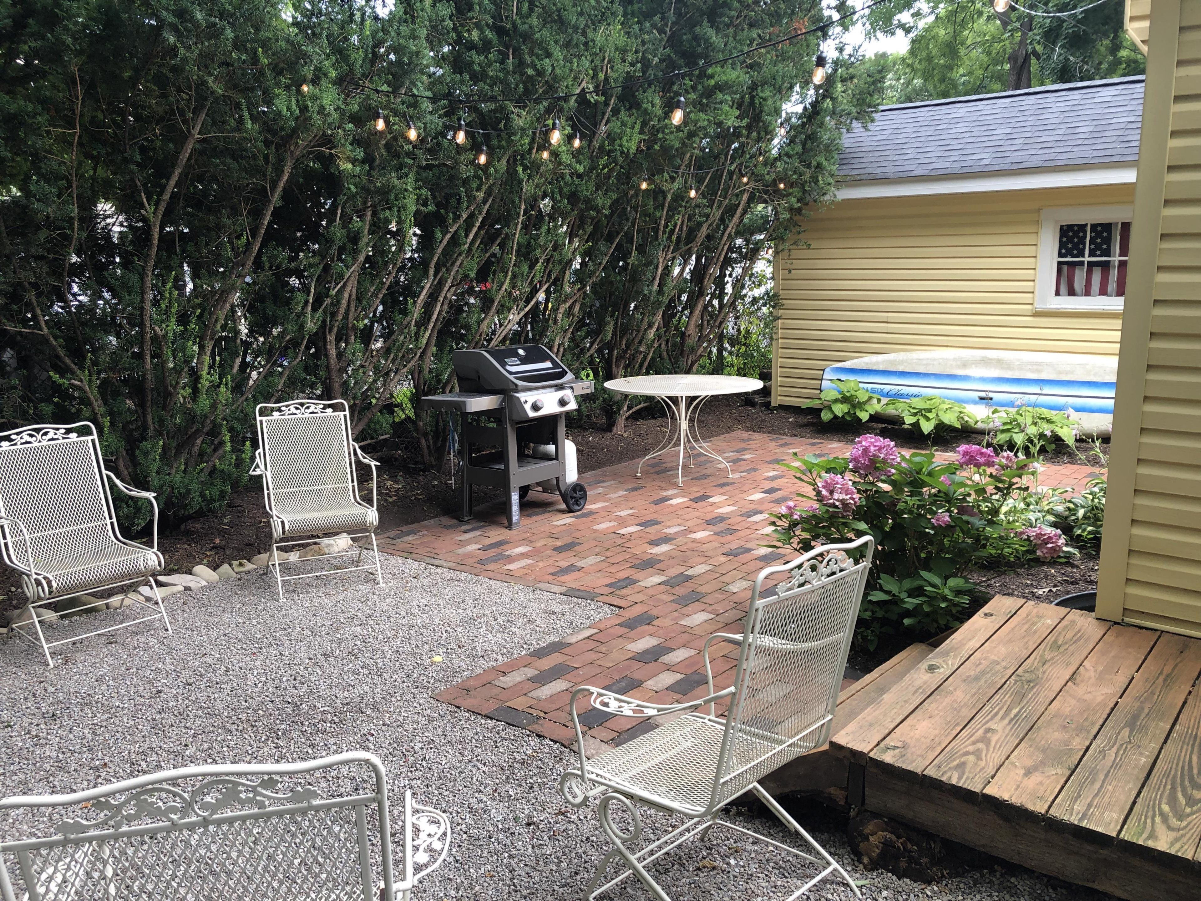 Une terrasse avec un barbecue, deux chaises, une table et une plateforme en bois.