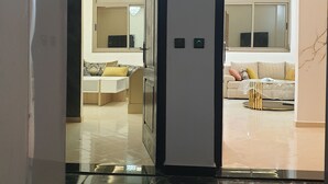A modern interior with a marble floor, a sofa with cushions, a dining area with a table, and a chandelier. - Apartment Bab Andalous III Tanger (Tanger)