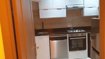 Eine moderne Küche mit weißen Schränken, einem Edelstahl-Geschirrspüler, einem Backofen und einem Kühlschrank.