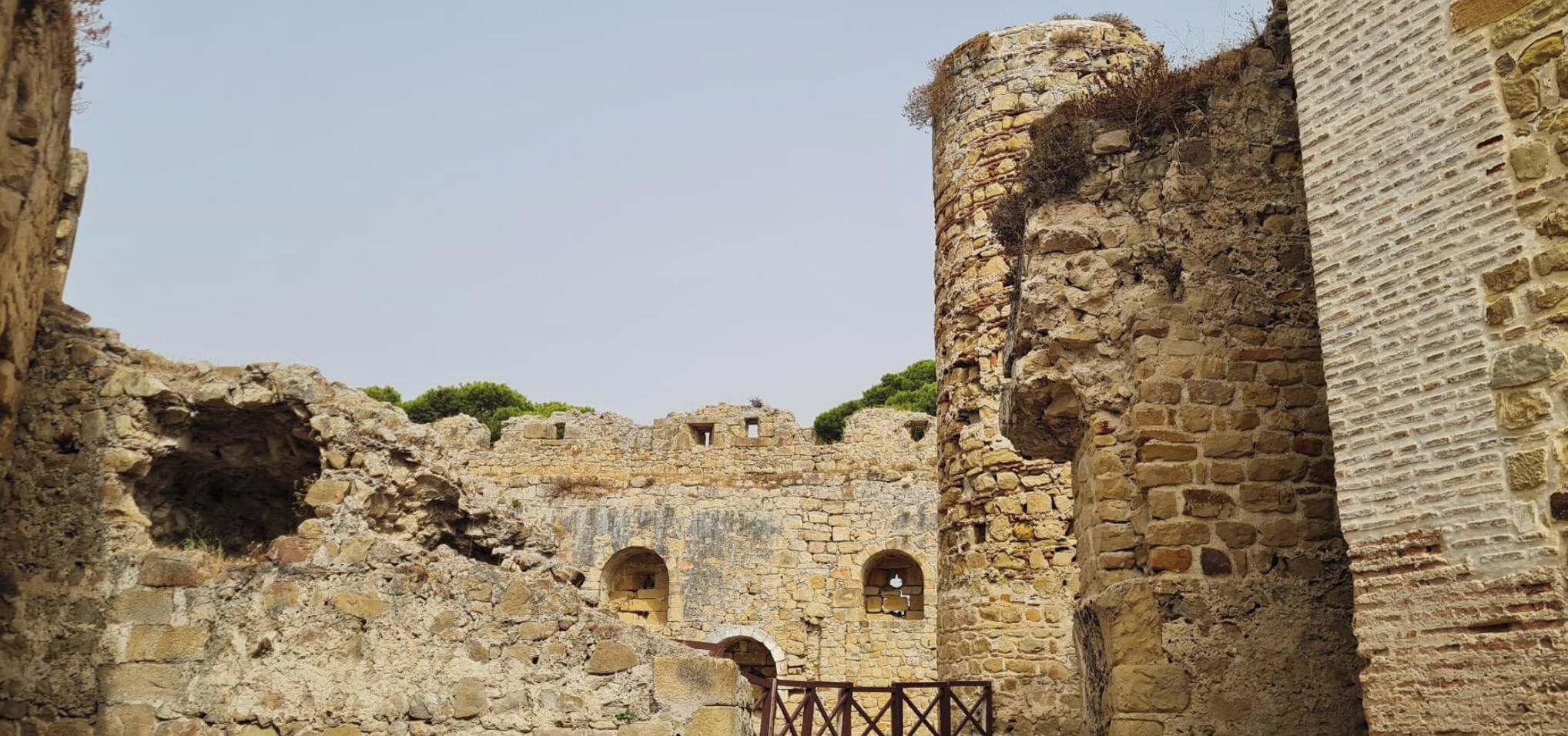 An ancient stone structure with arched openings and a fortified wall.