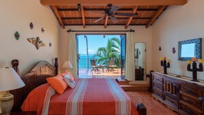 Un dormitorio con cama, mesita de noche, cómoda y vista al océano.