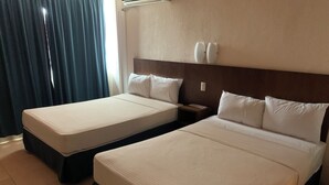 Habitación de hotel con dos camas individuales, una mesita de noche y un aire acondicionado instalado en la pared.