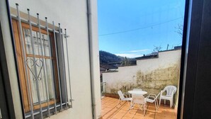 Eine Terrasse mit gefliestem Boden, einem kleinen Tisch und weißen Stühlen.