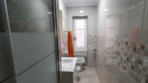 Ein modernes Badezimmer mit Duschkabine aus Glas, einem weißen Waschbecken und einer Toilette.