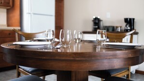 Mesa de madera redonda con platos, cubiertos y vasos dispuesta para cuatro comensales.