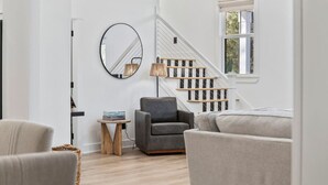 Een moderne woonkamer met een trap, een ronde spiegel en een lamp.