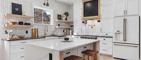 Una cocina moderna con armarios blancos, una isla grande con taburetes y un horno empotrado.