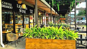 An outdoor seating area with wooden tables and chairs, surrounded by potted plants. - Modern Paradise Relax & Explore at Viva Jaco (Jaco)