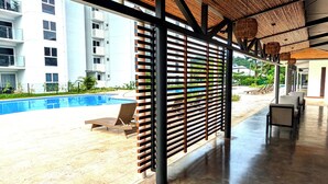 A covered outdoor area with a pool, wooden slatted ceiling, and lounge chairs. - Modern Paradise Relax & Explore at Viva Jaco (Jaco)