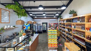 A café interior with a coffee bar, shelves of beverages, and a display of food items. - Modern Paradise Relax & Explore at Viva Jaco (Jaco)