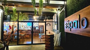 A restaurant with a wooden sign reading "Sepalo" and hanging plants. Inside, there are wooden tables and chairs, and a large window. - Modern Paradise Relax & Explore at Viva Jaco (Jaco)