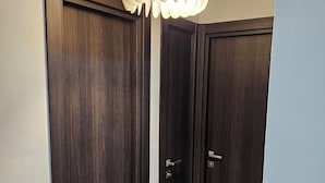A hallway with two dark wooden doors, a light switch, and a ceiling light fixture. - Charming 2-bedroom apartment in terrific Hollywood with AC, WiFi (Hollywood)