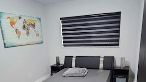 A modern bedroom with a large bed, a world map on the wall, and a window with blinds. - Charming 2-bedroom apartment in terrific Hollywood with AC, WiFi (Hollywood)