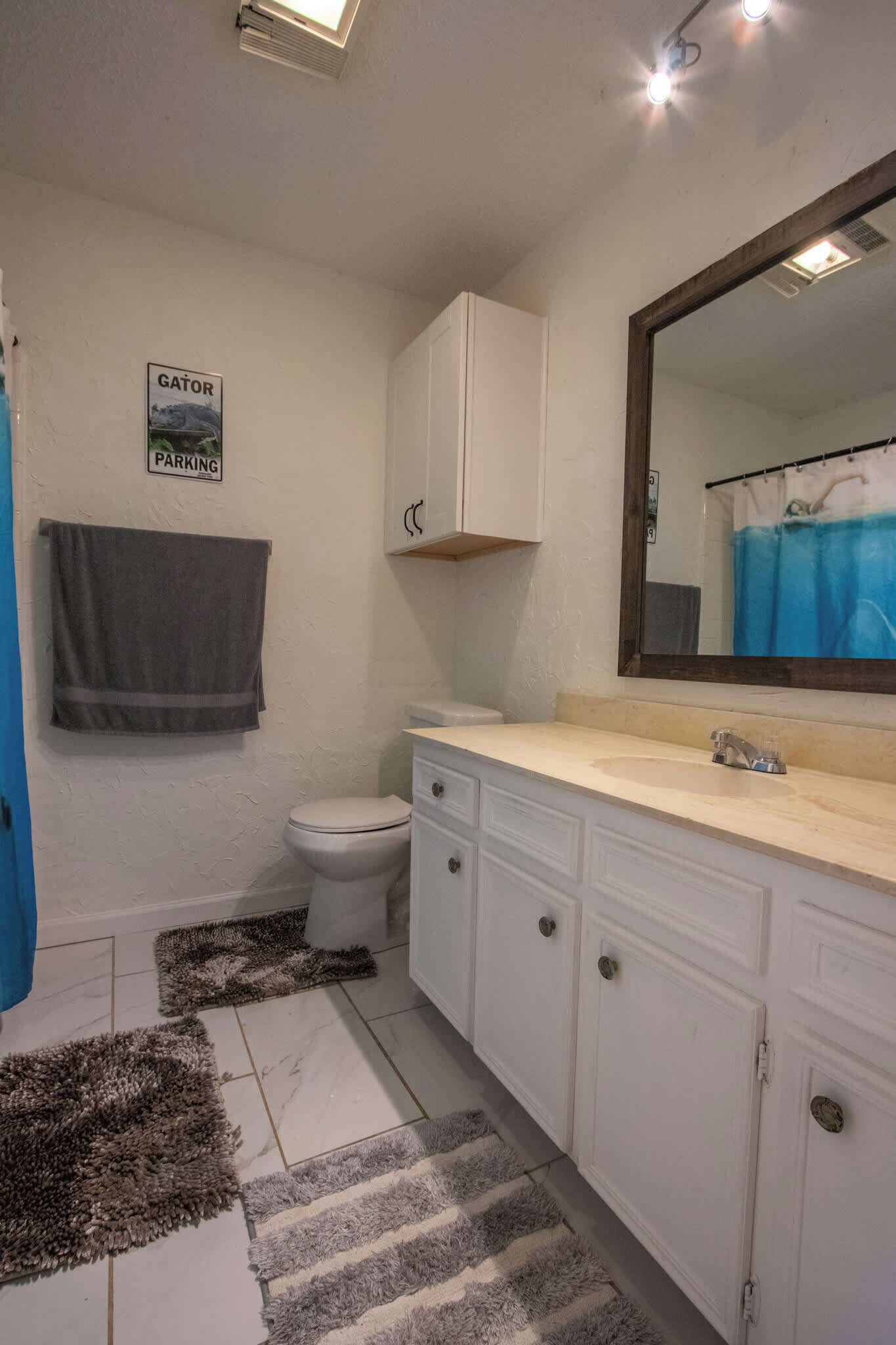 A bathroom with a toilet, a sink, a mirror, and a towel hanging on the wall.