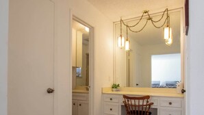 Une salle de bain avec un plancher en bois, un meuble-lavabo avec un miroir et une chaise.