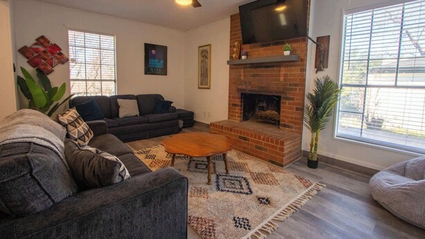 Un salon avec une cheminée, un ventilateur de plafond et un téléviseur.