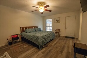 Ein Schlafzimmer mit Bett, Deckenventilator, Fenster und Tür.