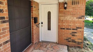 A brick exterior with a white door, a garage door, and a stone-paved entrance. - Spacious Stay for 16 - Central Fort Worth (Fort Worth)