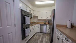A kitchen with white cabinets, a black oven, a stainless steel refrigerator, and a microwave. - Spacious Stay for 16 - Central Fort Worth (Fort Worth)