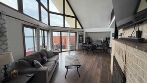 A spacious living area with a large window, a fireplace, and a dining area.