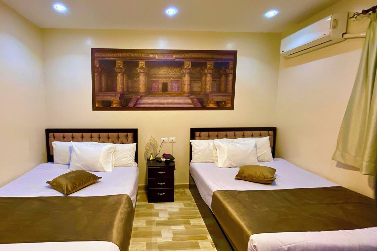 A hotel room with two beds, a nightstand, and a decorative wall piece.