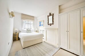 Une chambre à coucher comprenant un lit, des tables de chevet, une armoire, une fenêtre avec vue et un miroir fixé au mur.