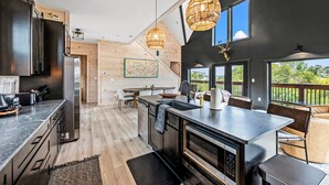 A modern kitchen with a large island, built-in appliances, and a dining area with outdoor seating. - Lakefront home with retro accents, private pool, and private dock. (Sevierville)