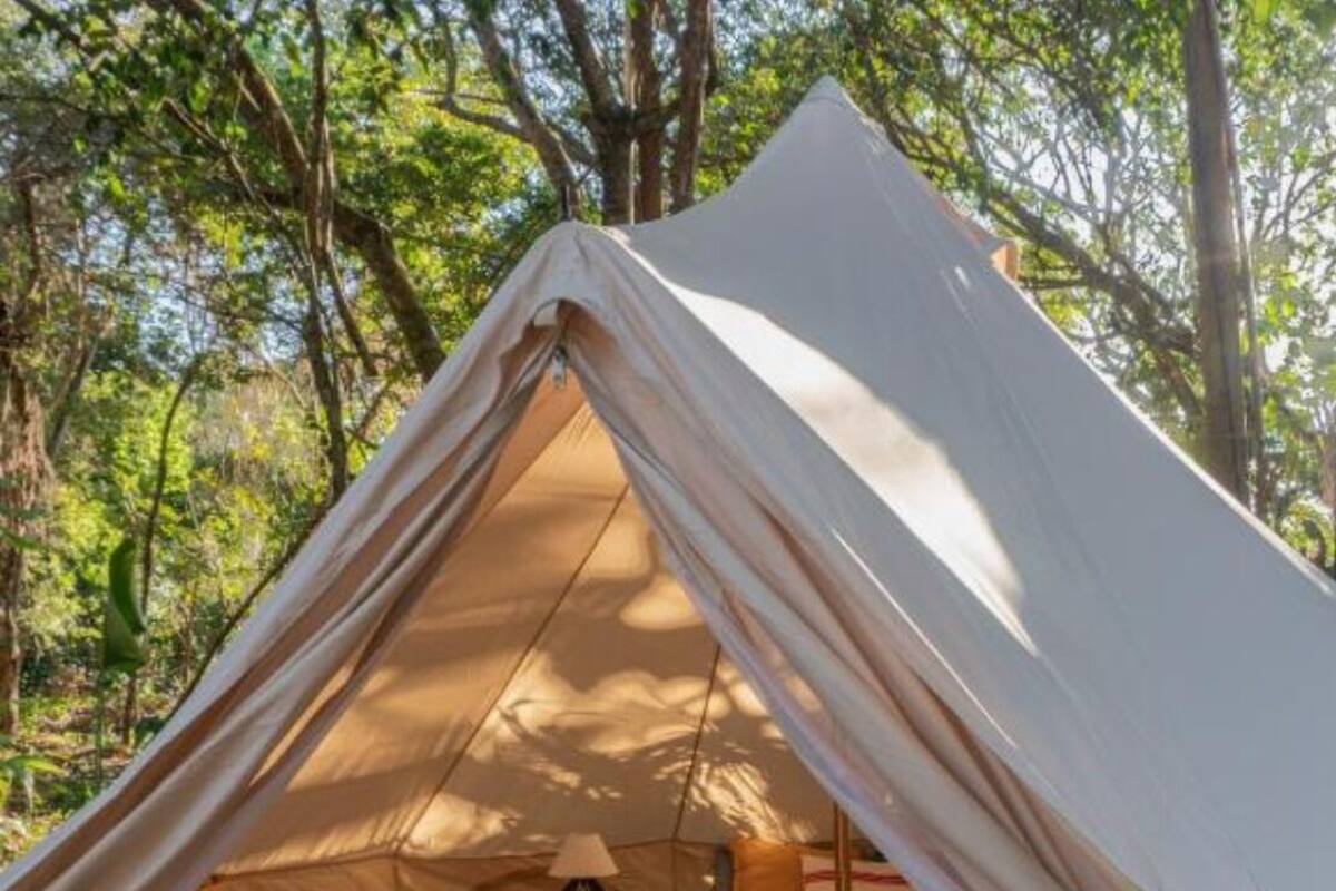 A tent with a bed, a table, and a chair inside.