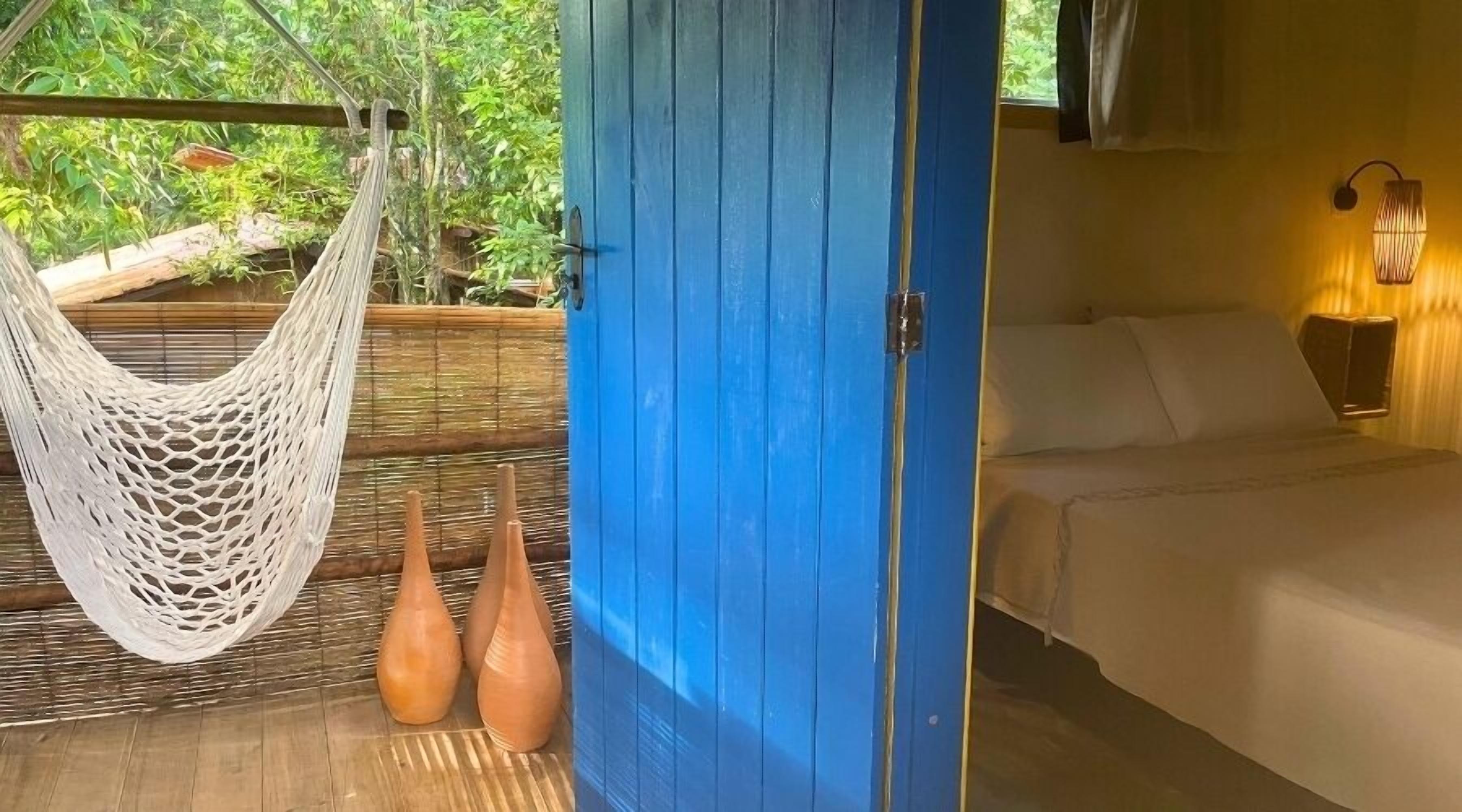 A room with a bed, a hammock, and two vases.