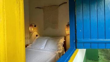 Una habitación con una cama, dos lámparas fijadas a la pared y una puerta azul.