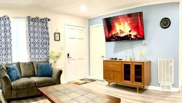 Een woonkamer met een bank, een salontafel, een aan de muur bevestigde televisie en een houten kast.
