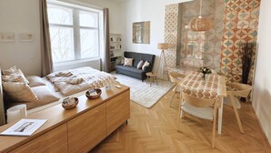A modern bedroom with a bed, bedside tables, a sofa, a dining table, and a floor lamp. - Superior Two-Bedroom Apartment (Budapest)