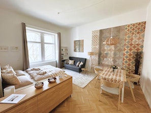 A modern bedroom with a bed, bedside tables, a sofa, a dining table, and a floor lamp. - Superior Two-Bedroom Apartment (Budapest)
