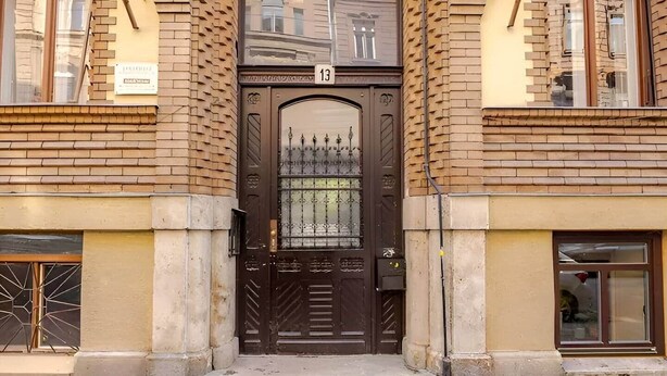 A building with a large, ornate entrance door, a brick facade, and a number '13' sign above the door. - Superior Two-Bedroom Apartment (Budapest)