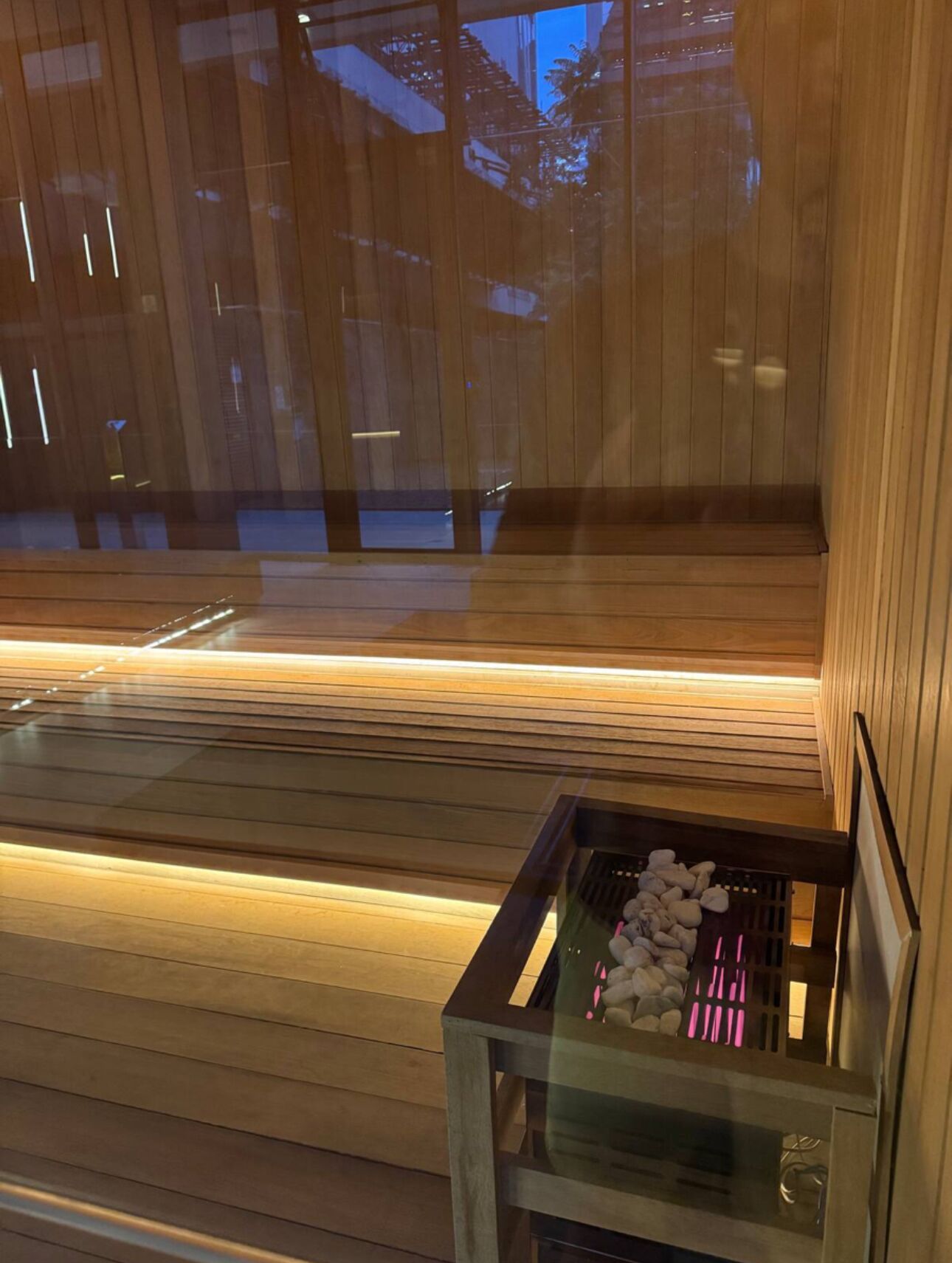 Un intérieur en bois avec une table en verre sur laquelle sont exposées des pierres et un banc.