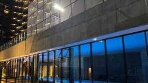 Moderni rakennus, jossa on suuret lasi-ikkunat ja uima-allasalue, jossa on sininen valaistus.