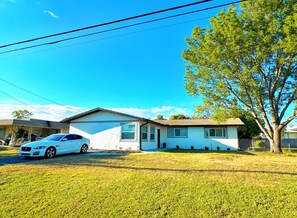 Ein eingeschossiges Haus mit Garage, Rasen und Baum.