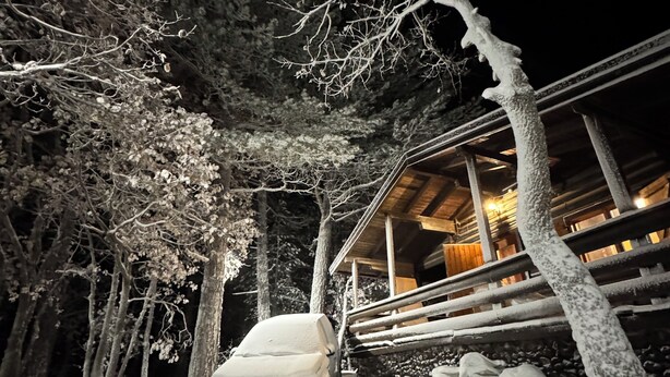 A snow-covered car parked in front of a building with a wooden exterior and a covered porch area. - Woods etna chalet (Sicilia)