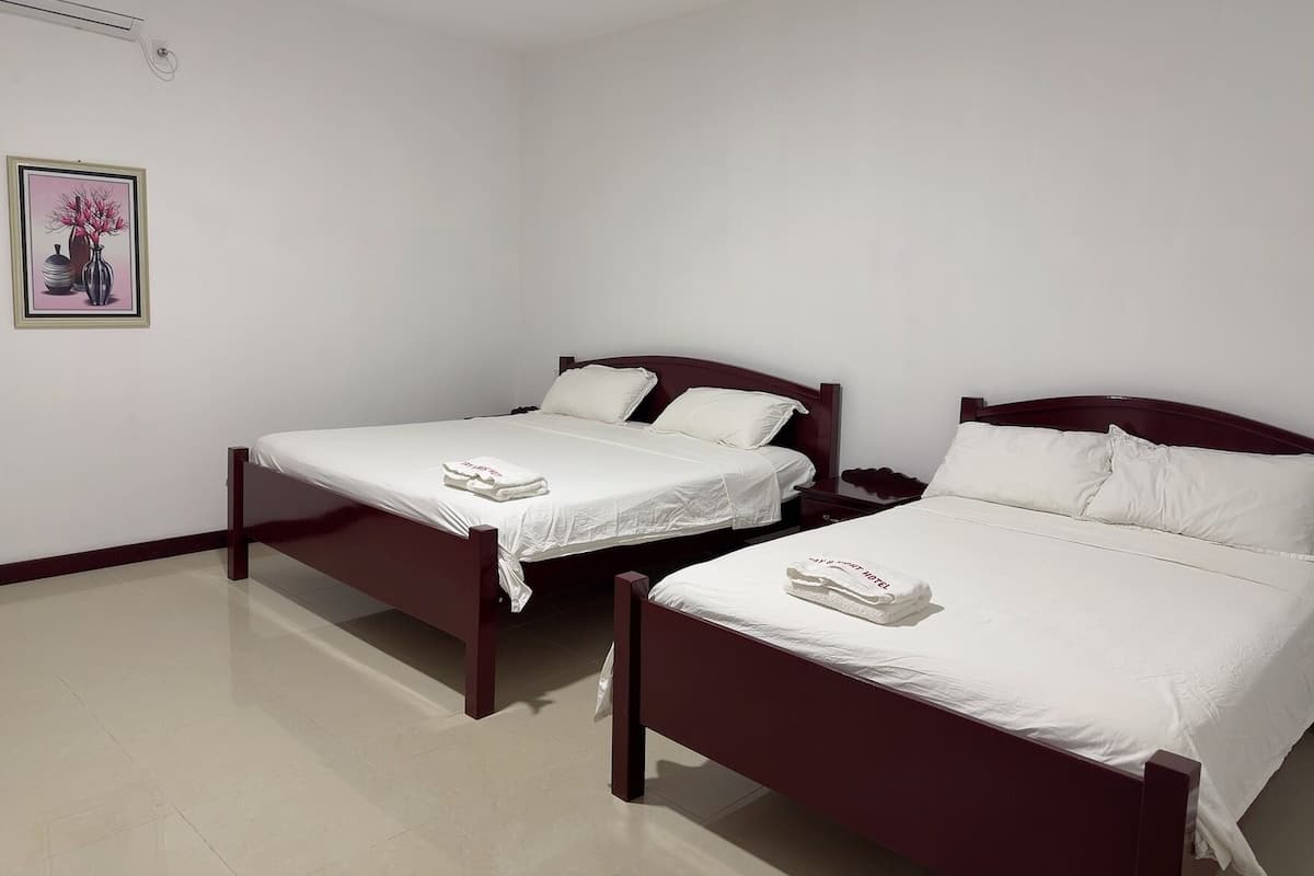 Habitación de hotel con dos camas individuales, una mesita de noche y un cuadro en la pared.