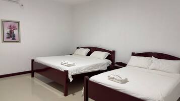 A hotel room with two single beds, a nightstand, and a framed picture on the wall.