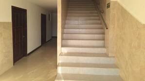 Una scala che conduce a un piano superiore, con una ringhiera su un lato e una porta in basso.