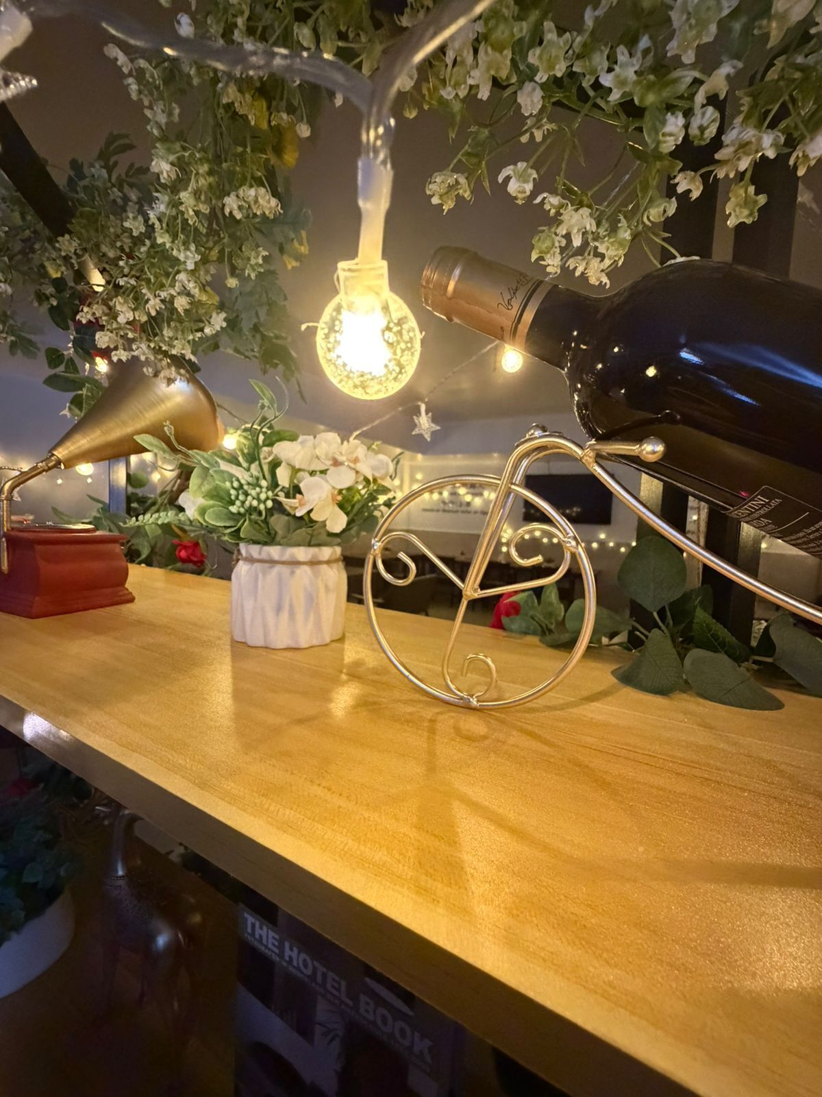 A table with a vintage-style lamp, a decorative bicycle, a bottle, and a light bulb.