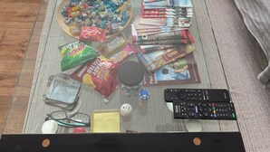 A glass-top coffee table with snacks, magazines, and a remote control. - Fresh Apartment & Parking (London)